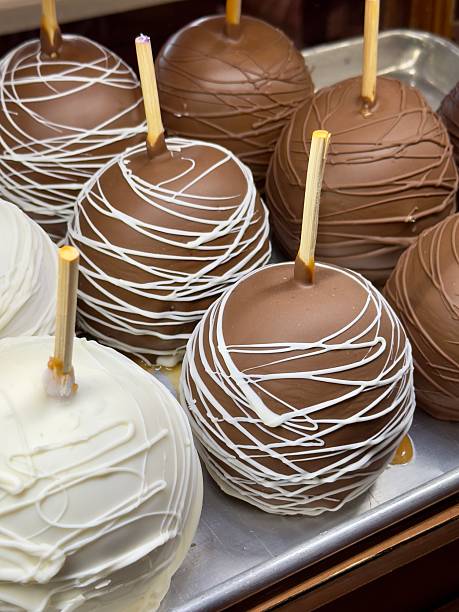 Caramel apples dipped in white and milk chocolate stick arranged at a candy store for a fall treat