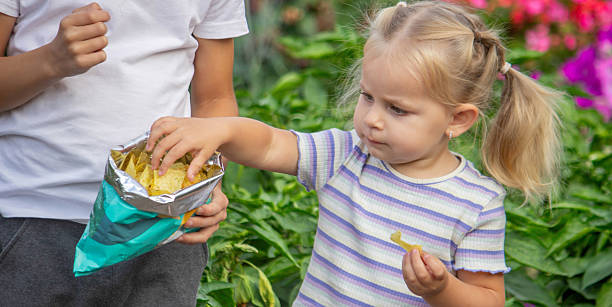 istock Boy and girl eating chips from a pack. Kid. 2236084768
