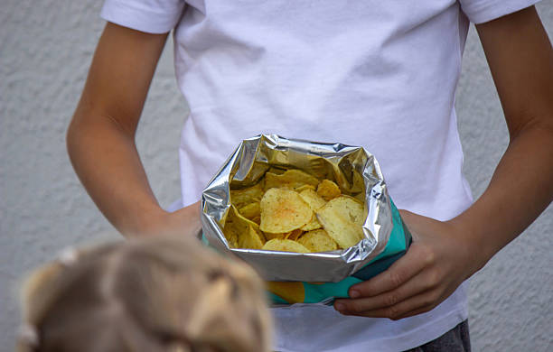 istock Boy and girl eating chips from a pack. Kid. 2236084794