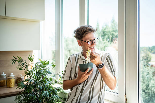istock Young man enjoying noodles for lunch in modern kitchen 2236085963