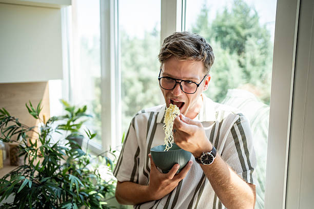istock Young man enjoying eating instant noodles for lunch 2236085969