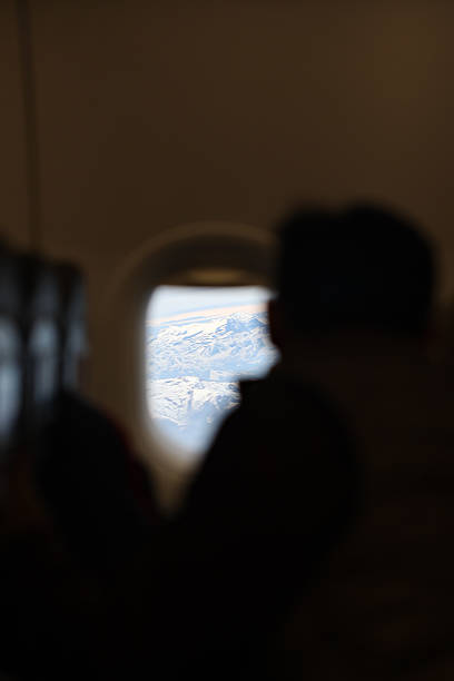 istock Person Watching the Alps Through Plane Window at High Altitude 2236087859