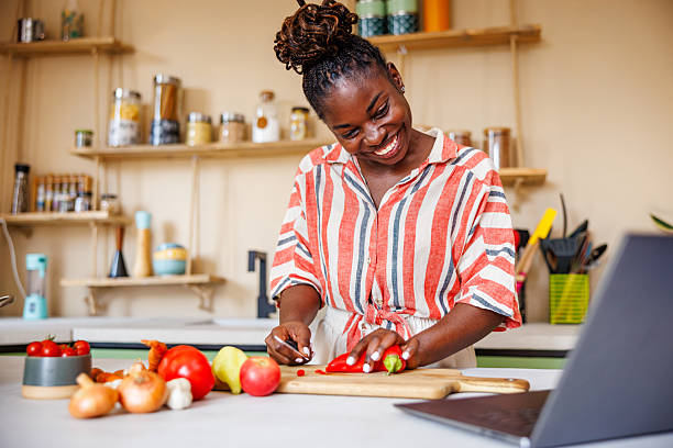 istock Smiling Black Woman Chopping Red Paprika While Learning How to Cook 2236091540