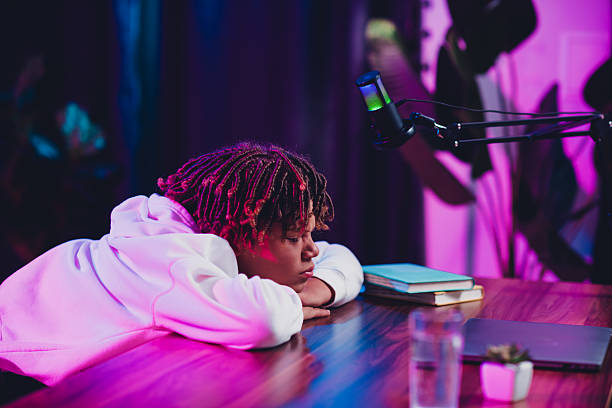 istock Young male content creator resting in a neon-lit room with podcast setup and laptop during an online streaming session 2236092073