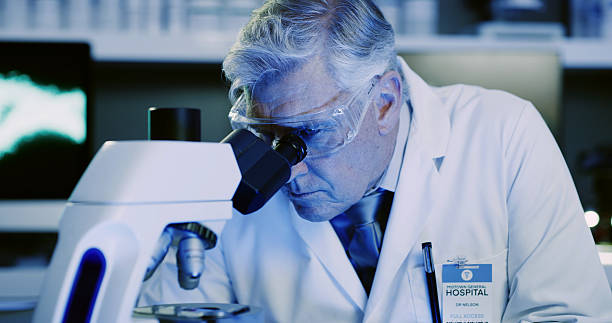 istock Man, scientist and sample with microscope in lab for research, medical experiment and testing dna. Mature person, equipment and particles reaction, genetic engineering and studying virus for biotech 2236096507
