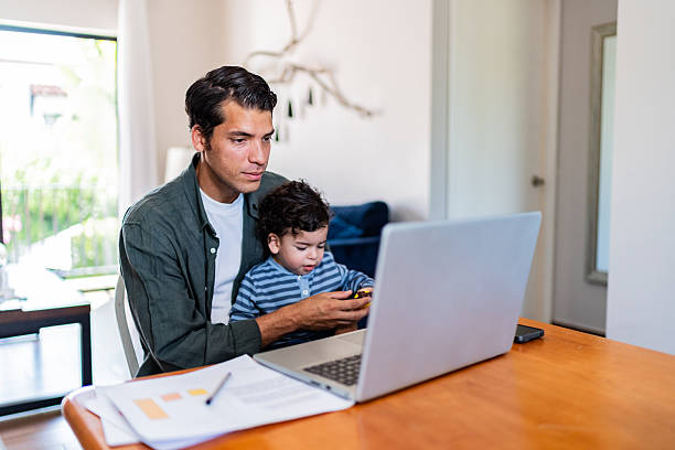 istock Young man working while holding his baby son at home 2236096794
