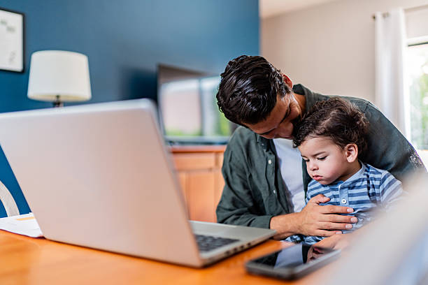 istock Young man working while holding his baby son at home 2236096796