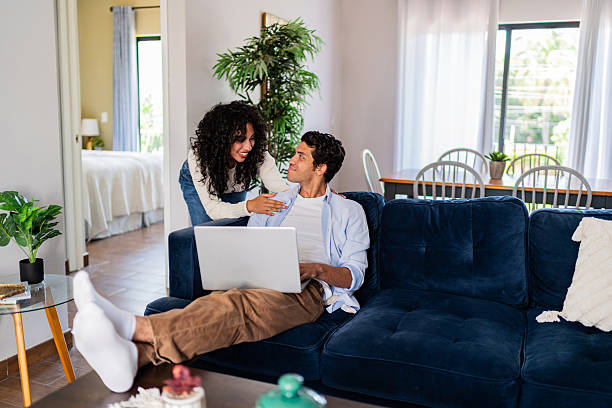 istock Young woman arriving and taking to husband while he using laptop at home 2236099408