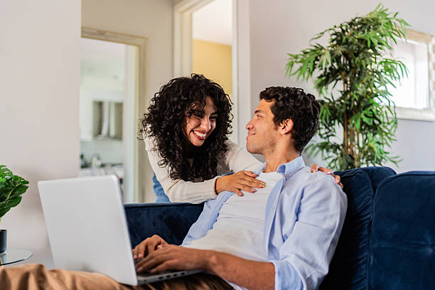 istock Young woman arriving and taking to husband while he using laptop at home 2236099941