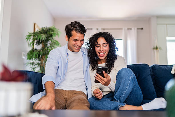 istock Young couple talking and using mobile phone at home 2236099971