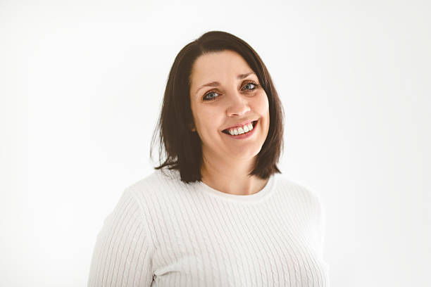 istock Real and authentic mature woman looking at camera and smiling while standing against white background 2236101604