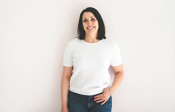 istock Real and authentic mature woman looking at camera and smiling while standing against white background 2236101606