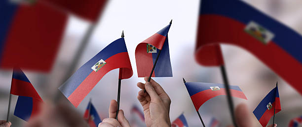 Haiti flags in their hands on a blurred urban background. The photo illustration was created without the use of artificial intelligence, only using Photoshop.