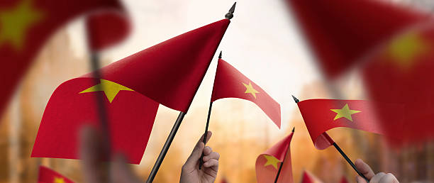 istock Vietnam flags in their hands on a blurred urban background 2236101973