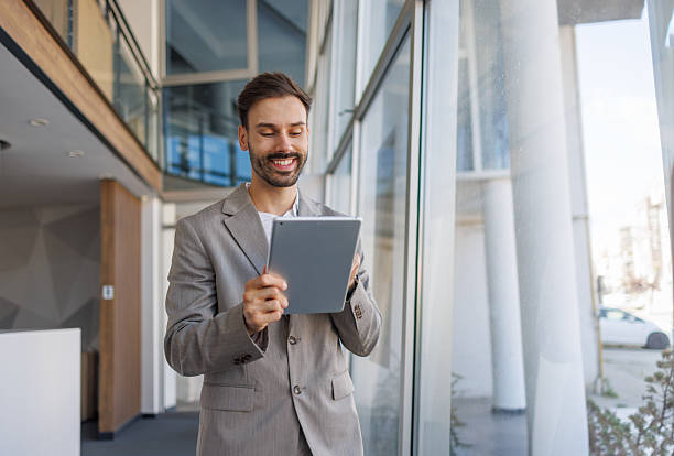 istock Smiling businessman using a digital tablet in modern office 2236108256