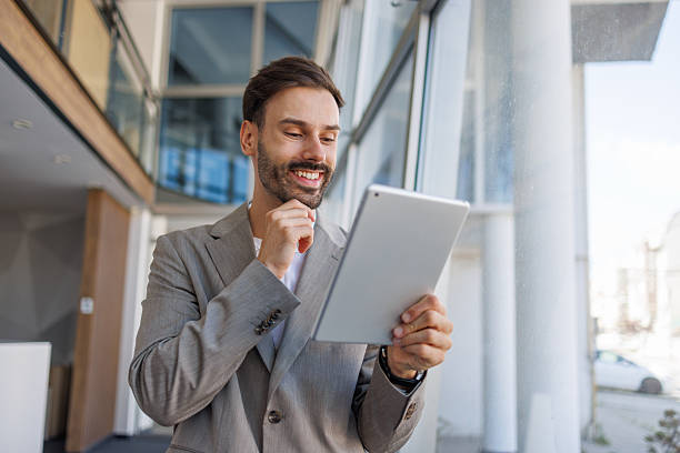 istock Businessman smiling while working on digital tablet in office 2236108282
