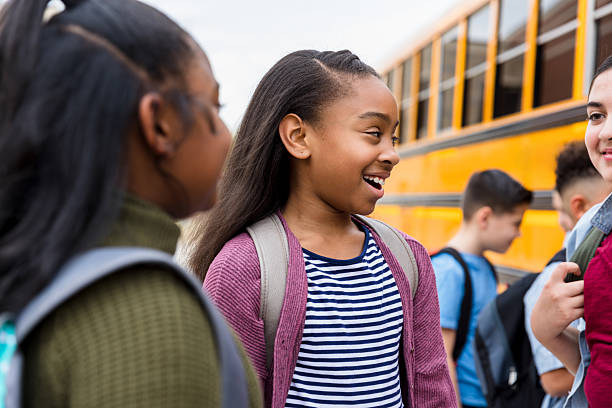 istock Happy elementary school girls chatting near school bus 2236109332