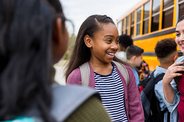 istock Happy Elementary School Girls Chatting Before School Bus 2236109343