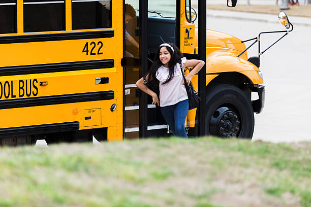 Smiling elementary school student exiting a school bus.