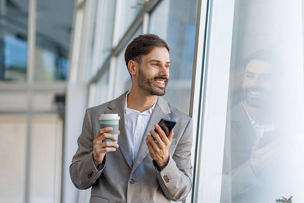 istock Businessman enjoying coffee break with phone in modern office 2236110594
