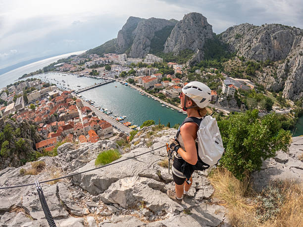 istock Woman Climbing Rocky Cliff Overlooking Harbor 2236110872