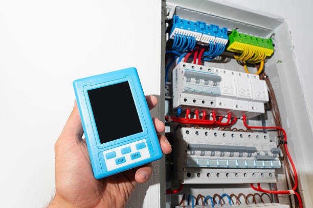 istock Hand holding portable measuring device with blank screen near open electrical panel, ready for design mockup. 2236111304