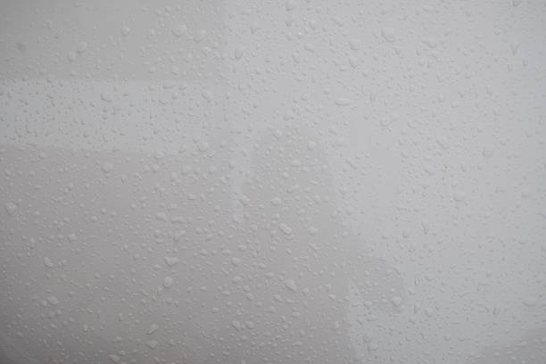 Close-up of a white surface covered with many small frozen water droplets. The droplets are scattered across the surface, creating a frosty texture.