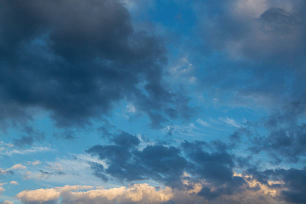 istock Wind-torn dark clouds rush toward the horizon where sunset light reflects the texture of clouds in the blue sunset hour before twilight. 2236112663