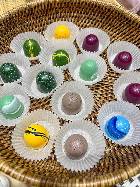 Colorful assorted chocolate bonbon collection in paper cups arranged in woven basket, bright artisanal candy selection with playful patterns