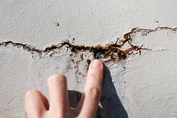 istock Person inspecting crack in wall with water seeping out. 2236114554