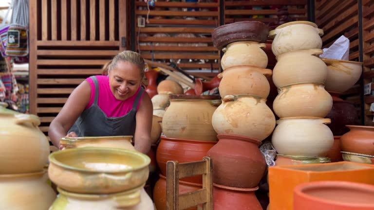 Ecuadorian mature afro female Artisan arranging handmade terracotta pots in Cuenca, Azuay, Ecuador // Happiness backpacker afro female tourist shopping souvenirs in a street market in Cuenca, Azuay, Ecuador