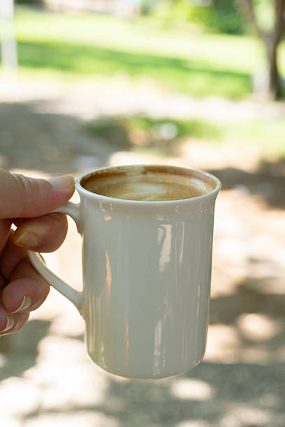 Warm cup of coffee held in hand. Morning coffee in hand. Hand holding cup of coffee. Coffee mug in hand close up. Hot coffee mug being held.
