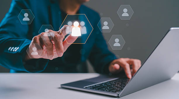 istock A person interacts with digital icons representing people while using a laptop, showcasing technology and virtual communication. 2236117381