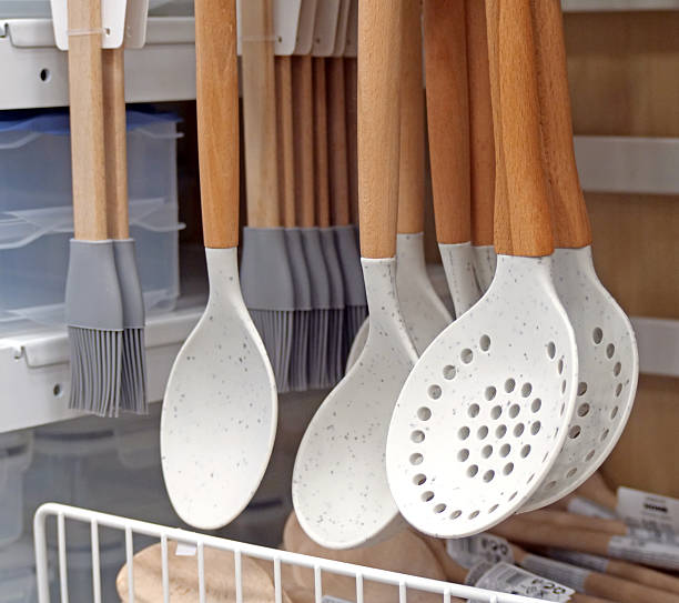 istock Wooden and silicone kitchen tools - A display of modern kitchen utensils, including white silicone spatulas and slotted spoons with natural wood handles, hanging in a store 2236119239