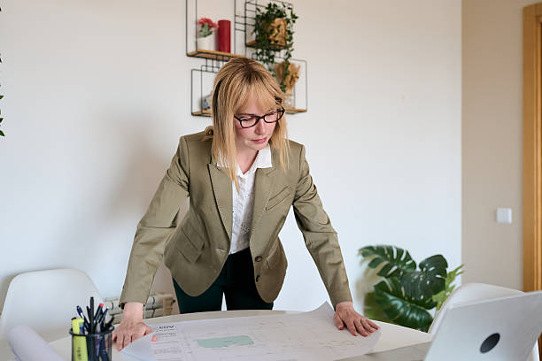 istock Woman architect reviewing blueprint plans in office 2236120081