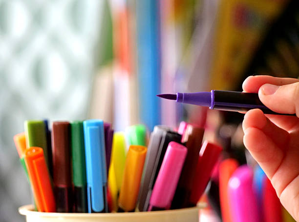 istock A close-up on a person's hand as they select a purple felt-tip pen from a holder filled with many other colorful markers 2236120134