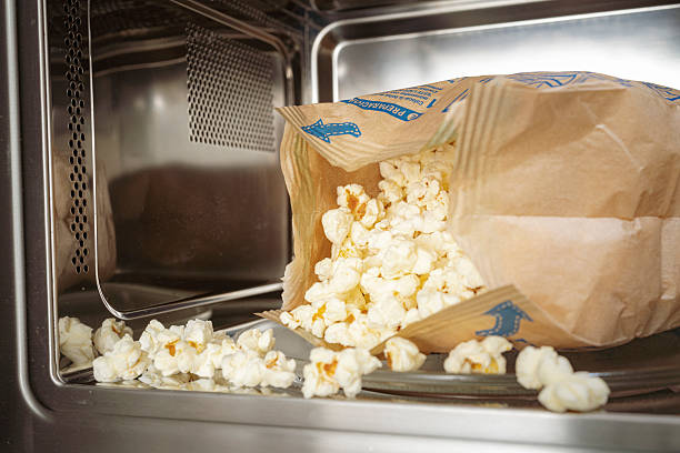 Popcorn bag in the microwave oven. Preparing snack using home appliance. Popcorn are spilled in the microwave oven interior