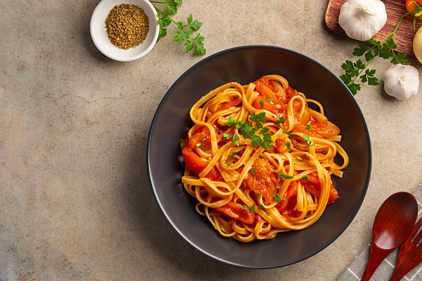 istock Fettuccine pasta with fresh tomatoes sauce in black plate. 2236121560