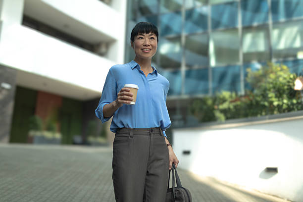 istock Asian businesswoman walking, holding coffee, starting workday 2236122321