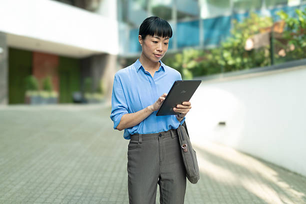 istock Asian businesswoman using digital tablet walking urban environment 2236122335