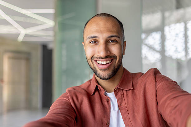 istock A happy man smiles and takes a selfie inside a modern office setting. 2236123335