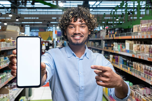istock Person demonstrating smartphone with blank screen inside a supermarket aisle 2236123971