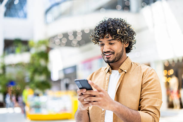 istock Smiling man in bright environment interacting with his smartphone 2236123974