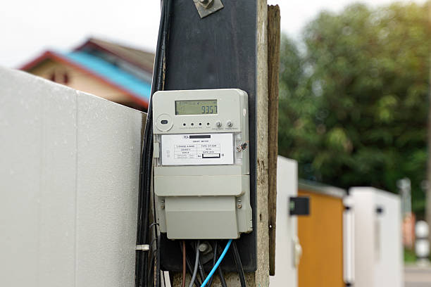 istock A PEA Smart Meter on an electricity pole displays 9357. Wires connect the gray meter, with a blurred house in the background, showing essential residential power infrastructure. 2236125408