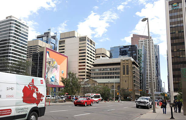 Calgary, Canada - August 20, 2025: Looking northeast from the south side of 6th Avenue Southwest. A mural by birdO, Jerry Rugg, stands among historic Knox United Church and modern office towers on 4th Street Southwest.  Summer afternoon with light clouds.