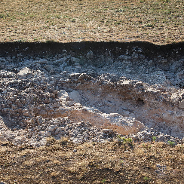 Exposed scientific work archaeological dig site showing soil layers and chalky surface, daylight photo, natural terrain, concept of ancient history excavation
