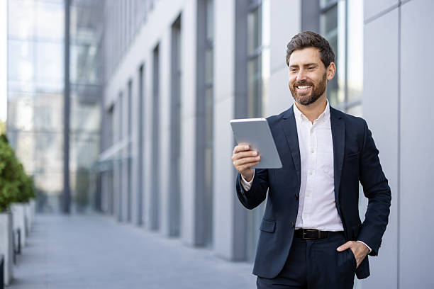 istock Businessman wearing a suit using a tablet outdoors near office buildings 2236132181