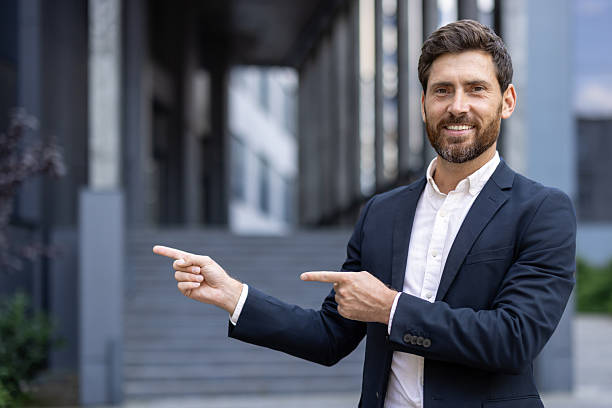 istock Confident businessman pointing sideways while standing outdoors in a modern urban area 2236132197