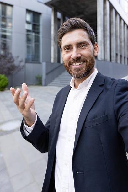 istock Smiling businessman making a video call outside a modern office building 2236132251
