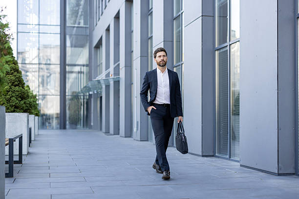 istock Confident businessman walking outside modern office building on a bright day 2236132284